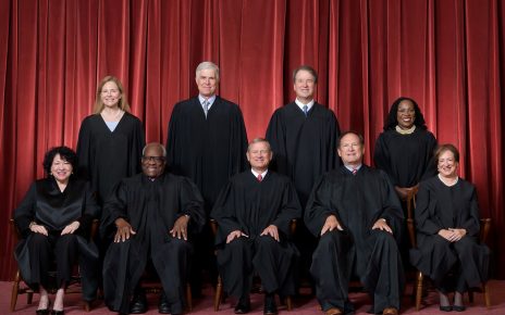 Formal group photograph of the Supreme Court as it was been comprised on June 30, 2022 after Justice Ketanji Brown Jackson joined the Court. The Justices are posed in front of red velvet drapes and arranged by seniority, with five seated and four standing. Seated from left are Justices Sonia Sotomayor, Clarence Thomas, Chief Justice John G. Roberts, Jr., and Justices Samuel A. Alito and Elena Kagan. Standing from left are Justices Amy Coney Barrett, Neil M. Gorsuch, Brett M. Kavanaugh, and Ketanji Brown Jackson.